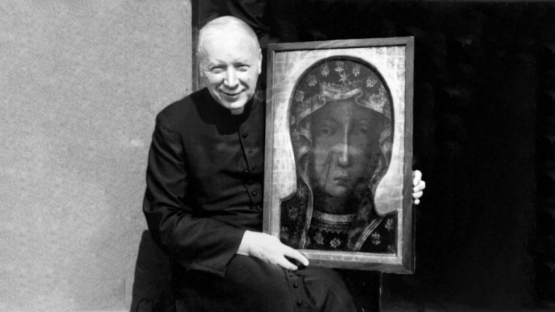 Siedzący błogosławiony Kardynał Stefan Wyszyński trzyma na kolanach duży obraz Matki Bożej Częstochowskiej