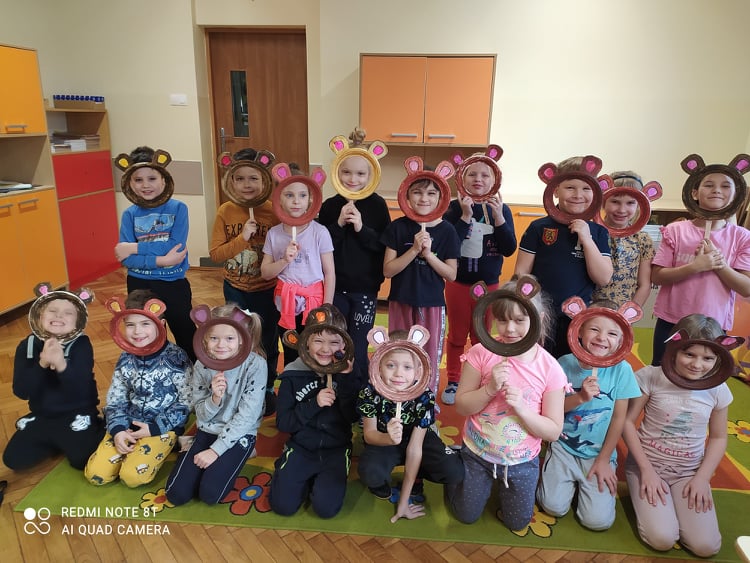 grupa dzieci z maskami misiów przyłożonymi do twarzy