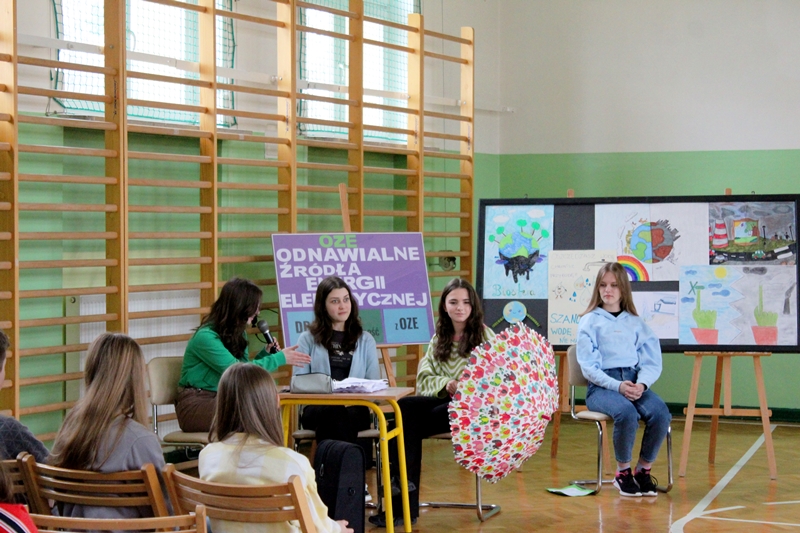 Na zdjęciu są uczennice 8 klasy, które rozmawiają o ekologii. Dziewczynka z prawej strony trzyma kolorowy parasol.