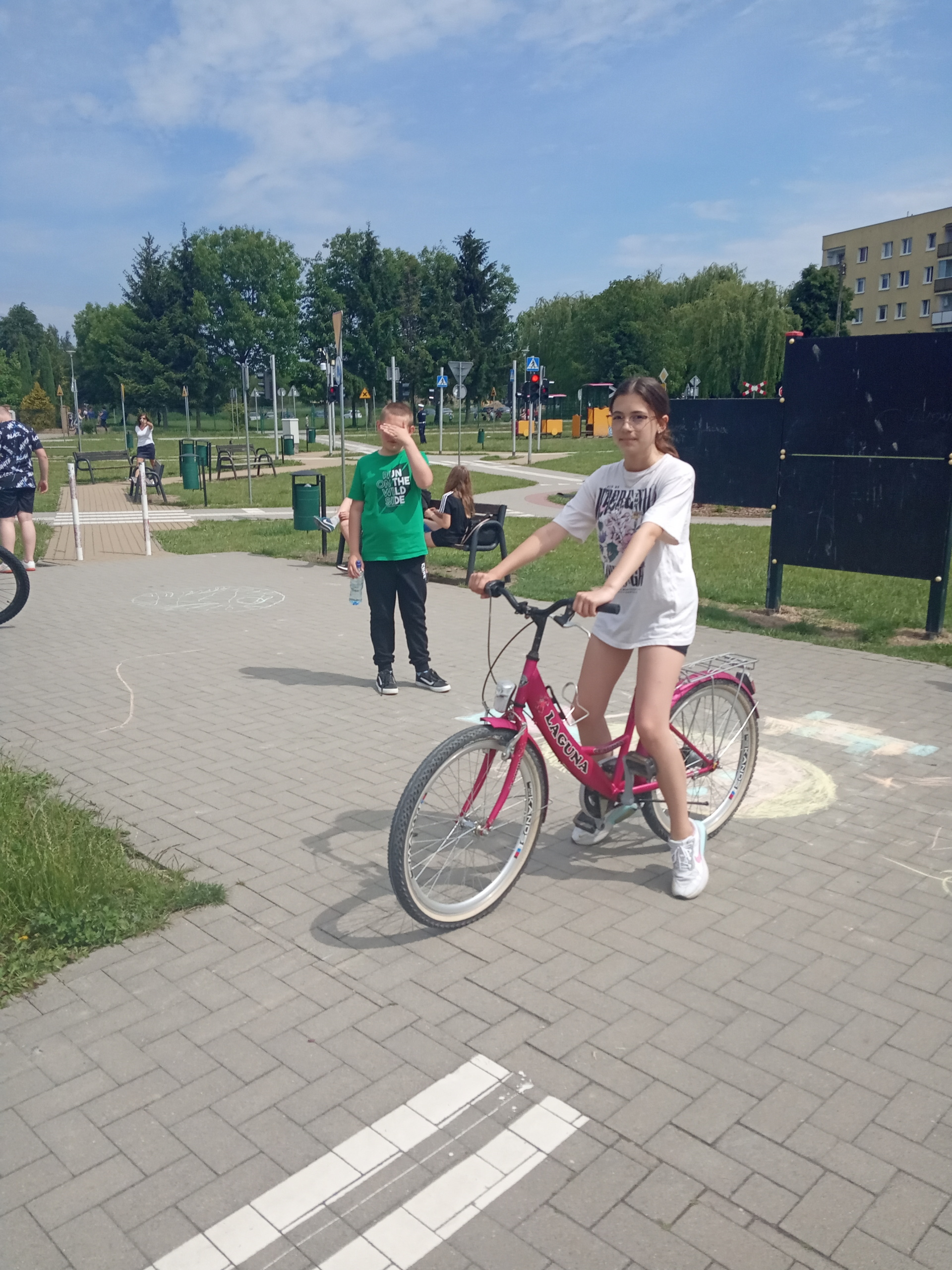 Uczennica przygotowuje się do jazdy rowerem po miasteczku rowerowym.