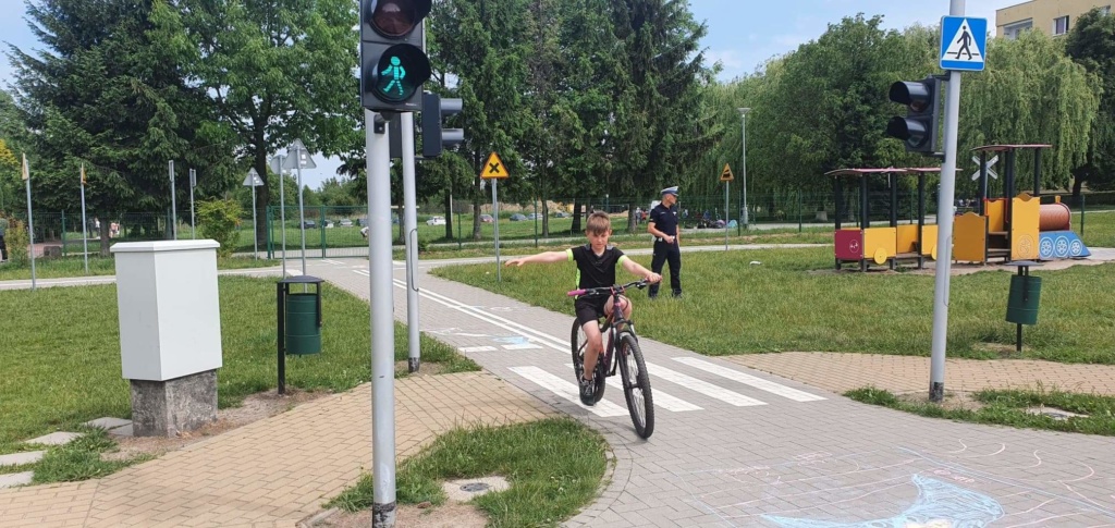 Uczeń jadąc na rowerze pokazuje prawa ręka manewr skrętu w prawo.