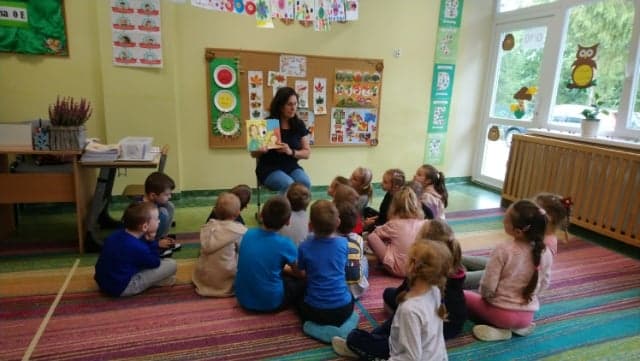 uczniowie klasy 0e w trakcie słuchania czytanej książki przez panią Irenę Zaniewską