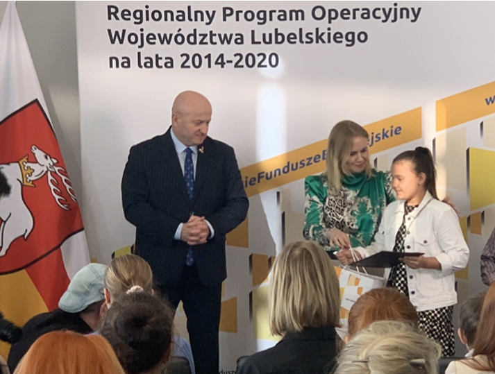 Marszałek Jarosław Stawiarski oraz Dyrektor Departamentu Zarządzania RPO Anna Brzyska wręczają dyplom i nagrodę uczennicy Karolinie Czerniak.