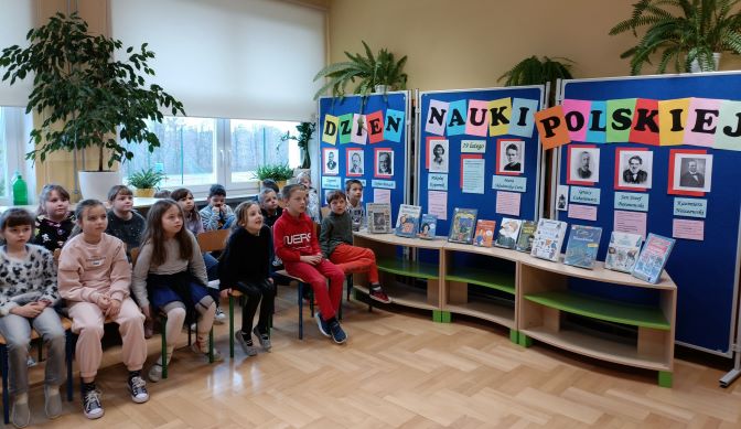 uczniowie klasy 2d na spotkaniu z okazji Dnia Nauki Polskiej. W tle widać gazetkę o słynnych naukowcach oraz wystawę książek