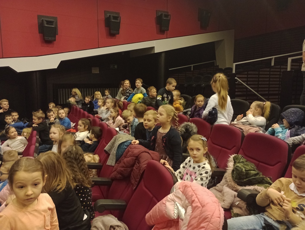 Grupa dzieci siedzących na fotelach w teatrze.