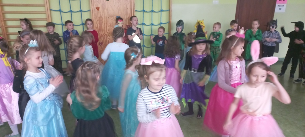 Zdjęcie przedstawia tańczące, wesołe dzieci w kolorowych strojach bawiące się przy muzyce