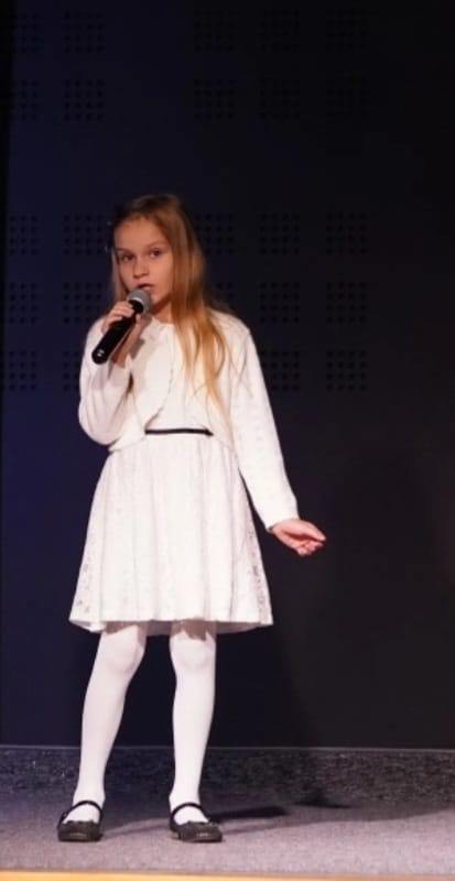  Zdjęcie przedstawia dziewczynkę śpiewającą podczas konkursu.