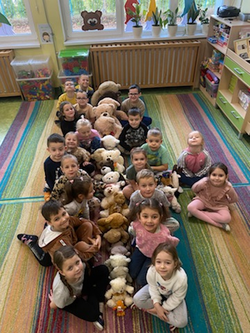  Dzieci siedzą na dywanie z misiami.