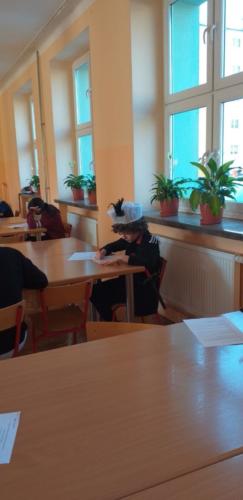 Uczniowie przy stolikach rozwiązują test konkursowy