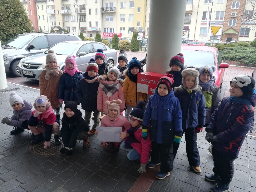 Uczniowie klasy 0 E z kartkami świątecznymi dla kombatantów przy skrzynce na listy.