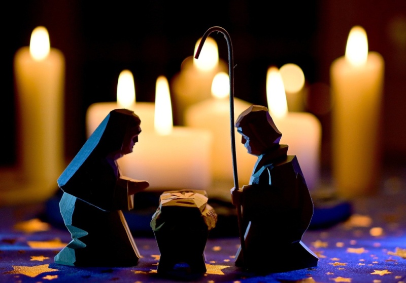 Maryja i Józef pochylają się nad Jezusem. W tle płoną świece