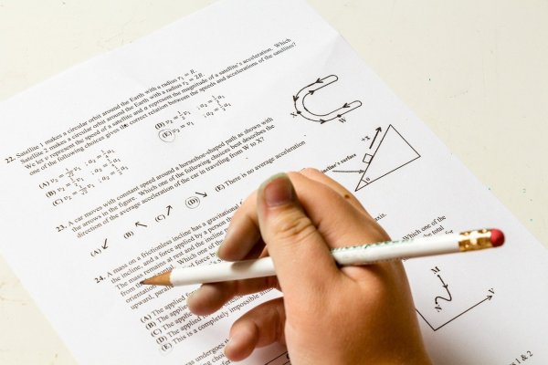 ręka trzymająca ołówek nad arkuszem egzaminacyjnym