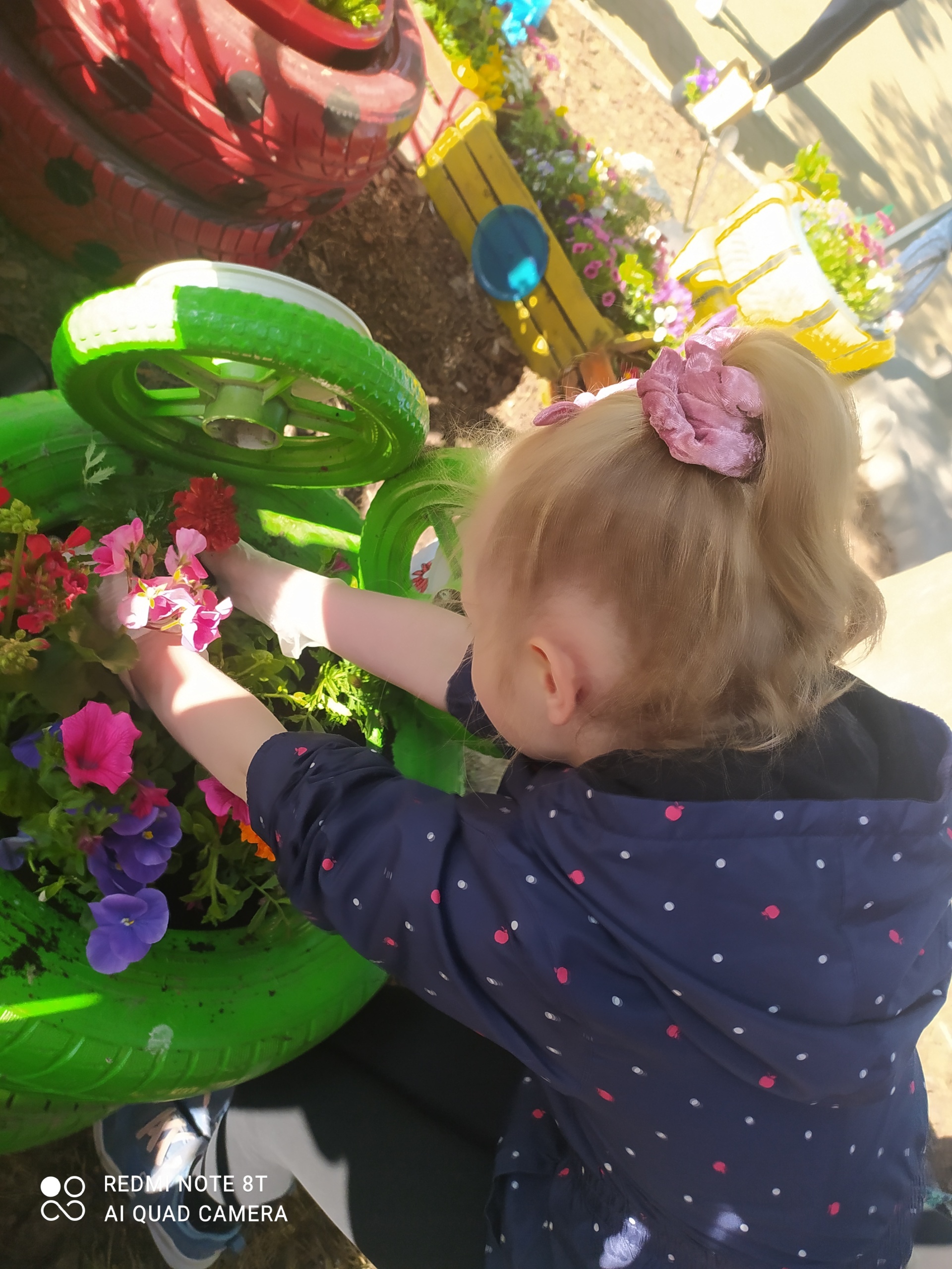 Dzieci sadzą kolorowe kwiaty w skrzynkach.