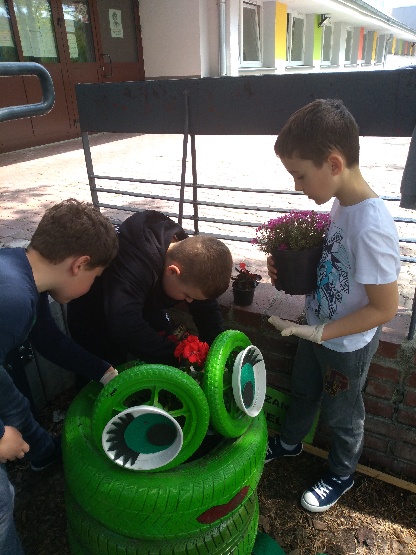 Dzieci sadzą rośliny do skrzynek.