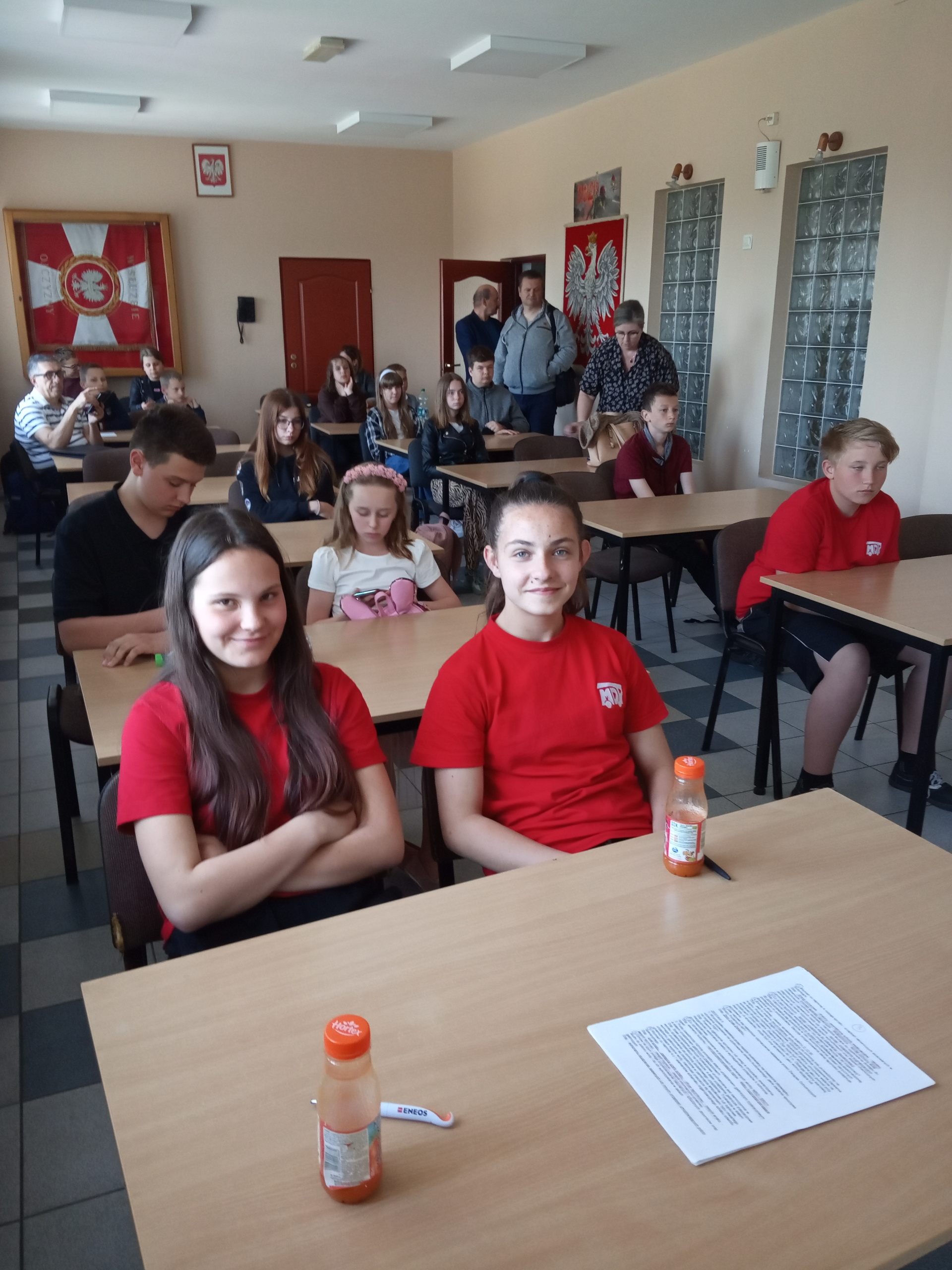Uczniowie siedzą w ławkach, słuchają odpowiedzi ustnych pozostałych uczestników.