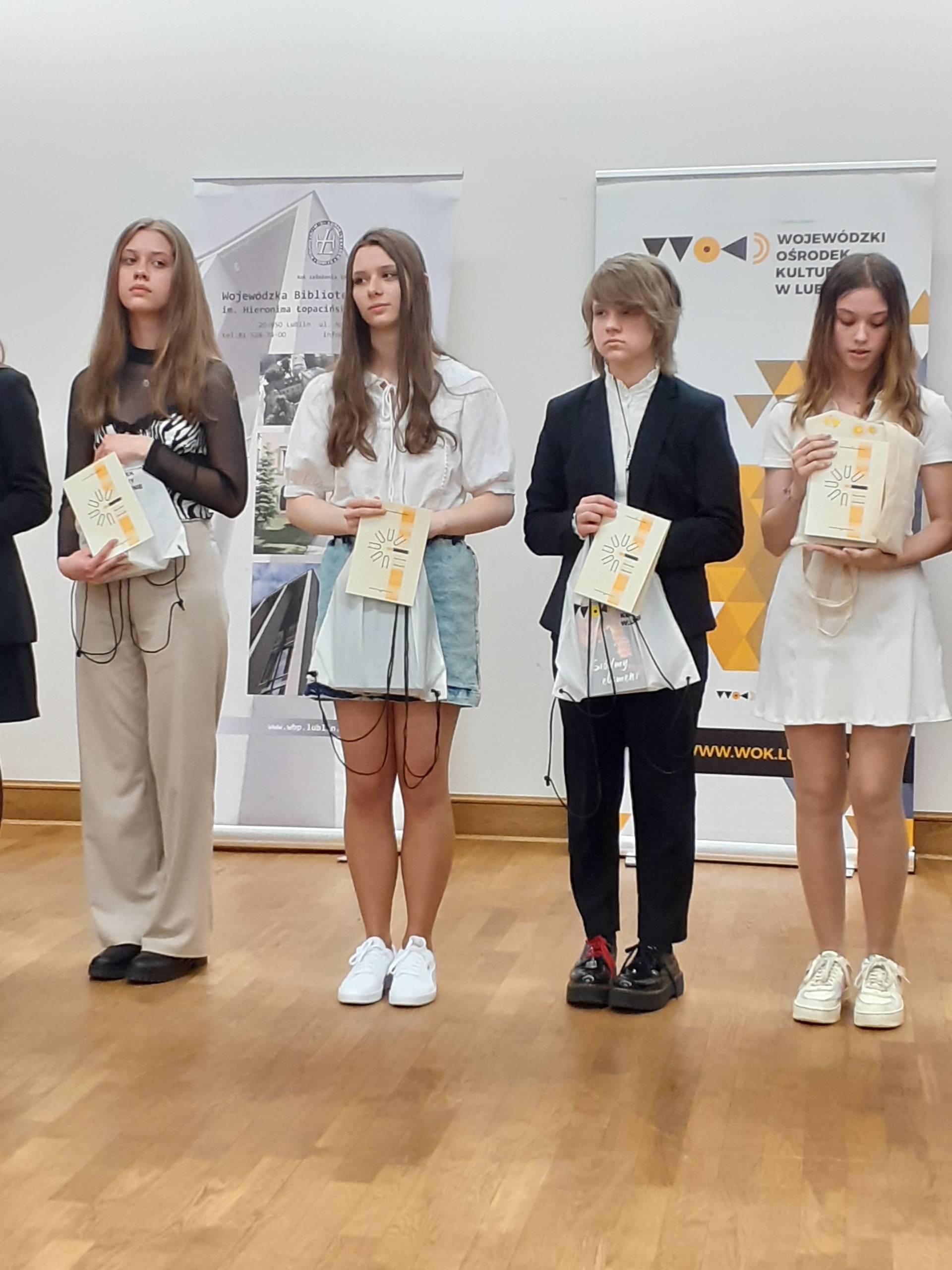 Zdjęcie przedstawia młodzież - laureatów konkursu literackiego, pozujących z dyplomami. 