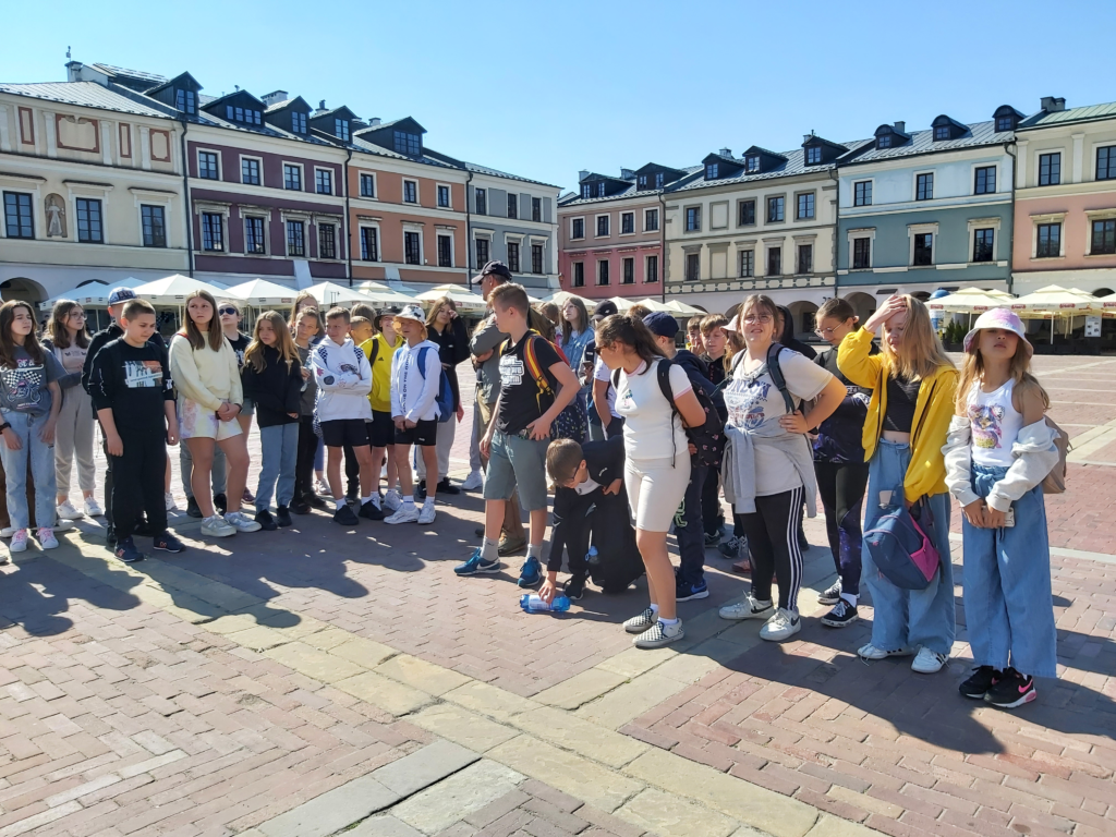 Grupa młodzieży stojąca na środku rynku w Zamościu.