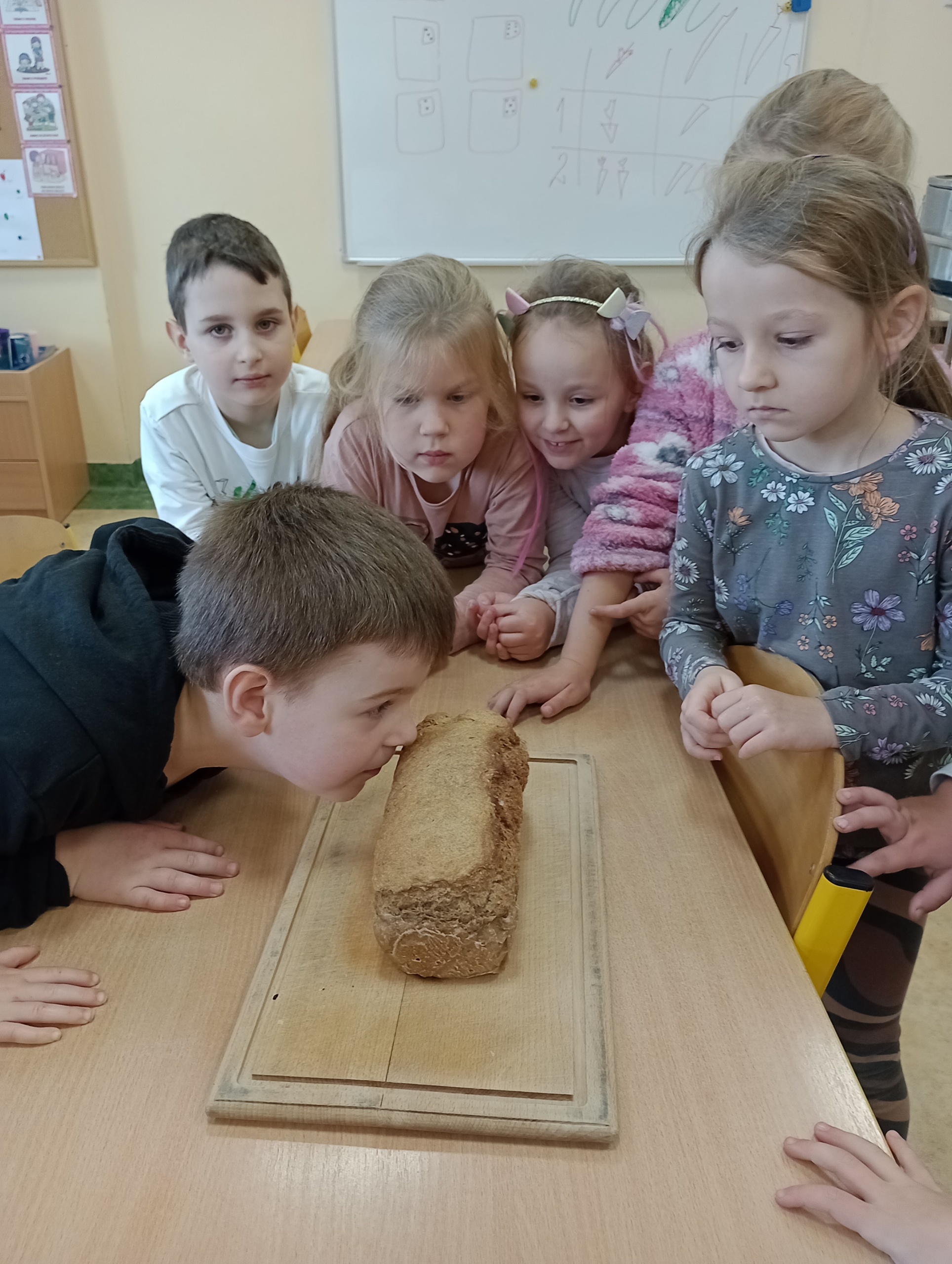 Dzieci wąchają świeżo upieczony chleb. 