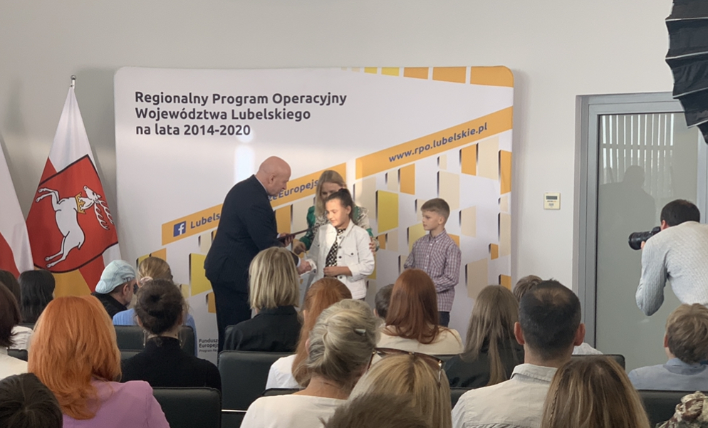 Marszałek Jarosław Stawiarski oraz Dyrektor Departamentu Zarządzania RPO Anna Brzyska wręczają dyplom i nagrodę uczennicy Karolinie Czerniak.