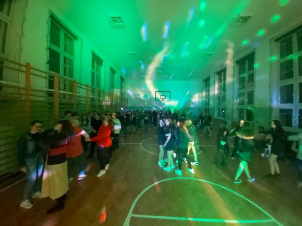 sala gimnastyczna w budynku przy ul. Piłsudskiego; dzieci tańczą w rytm muzyki; widać zielone światła dyskotekowe;