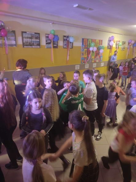 korytarz w budynku przy ul. Szkolnej; dzieci tańczą w rytm muzyki;