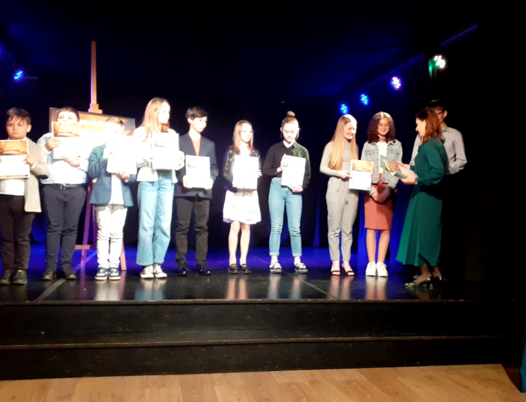 Laureaci Turnieju Poezji Dziecięcej stoją na scenie. Otrzymują dyplomy i nagrody.