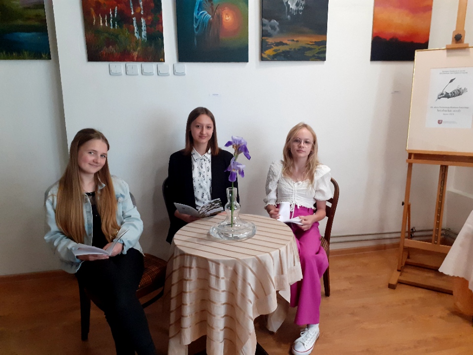 nagrodzone uczennice Emilia Cegłowska, Milena Sobiesiak i Pola Smolnik siedzą przy stoliku i prezentują swoje wiersze.