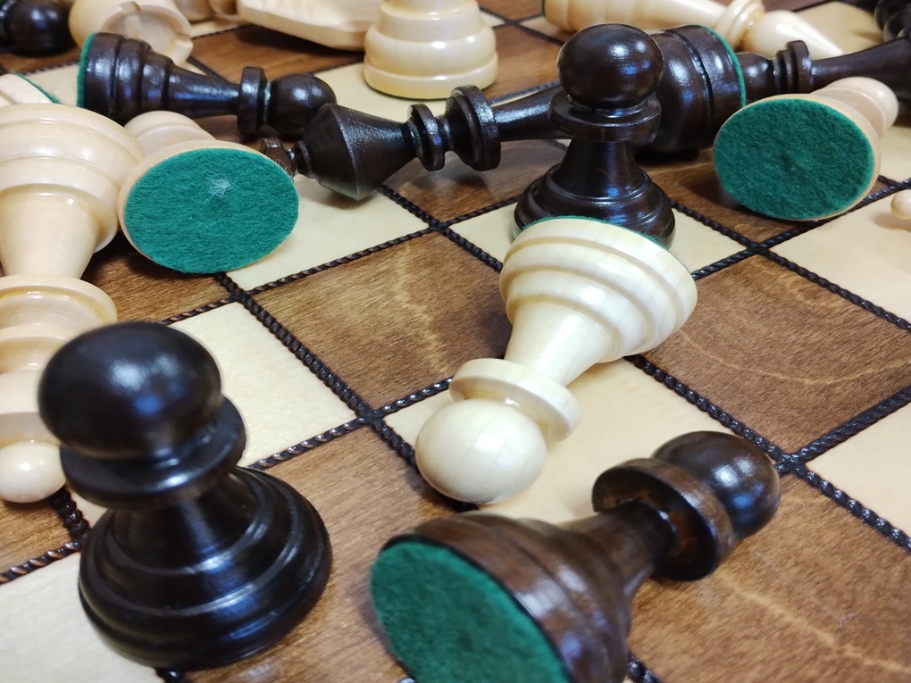 fotografia przedstawia drewnianą szachownicę i bierki szachowe