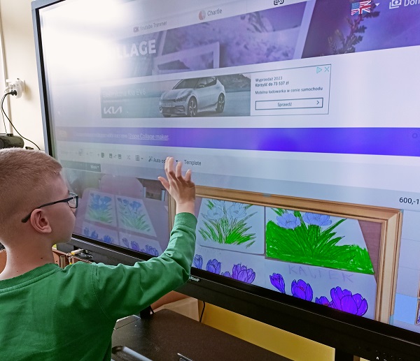 2. Chłopiec w zielonej bluzce dotyka ekranu interaktywnego.