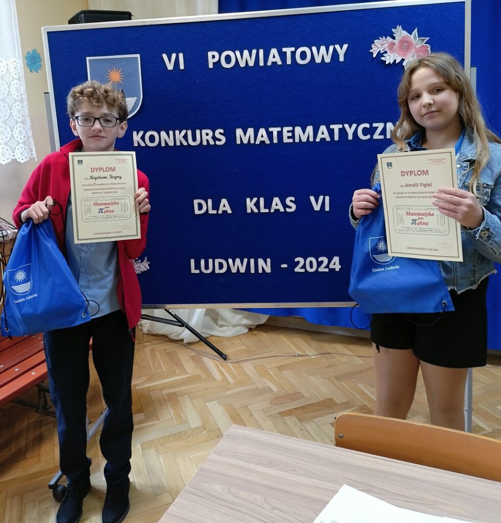 reprezentaci naszej szkoły Krystian i Amelia stoją przy tablicy z tytułem konkursu. W ręce trzymają dyplomy oraz niebieskie worki z nagrodami