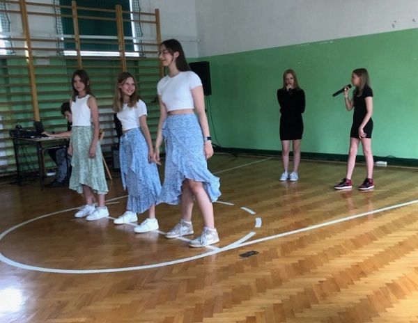 pięć dziewcząt tańczy i śpiewa w sali gimnastycznej
