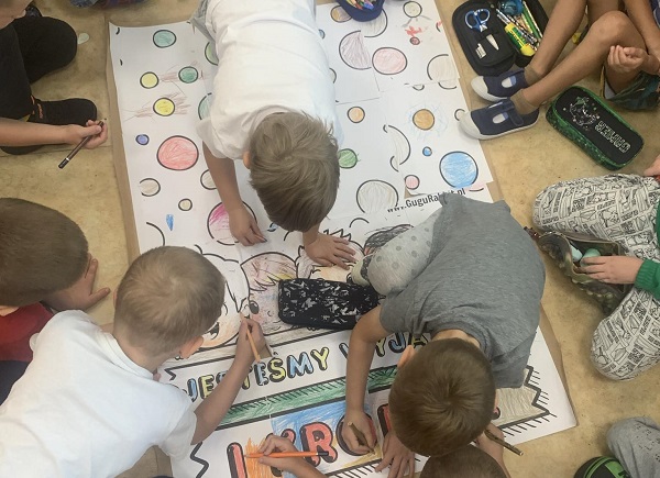 Grupa dzieci maluje kolorowankę wielkoformatową