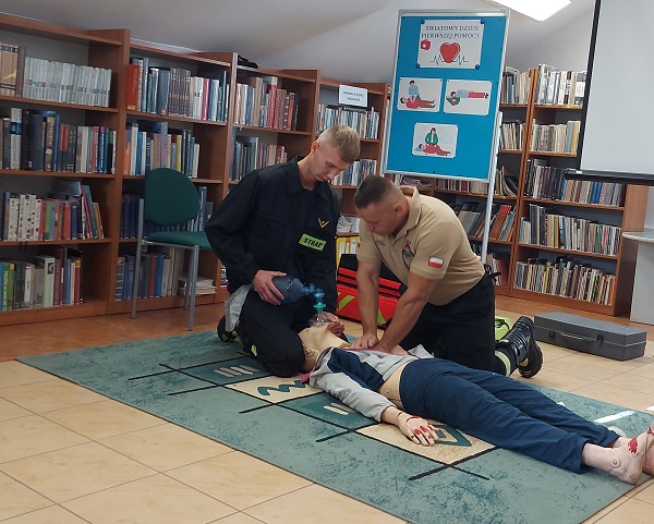 Dwóch mężczyzn demonstracje udzielanie pierwszej pomocy na leżącym na podłodze fantomie.