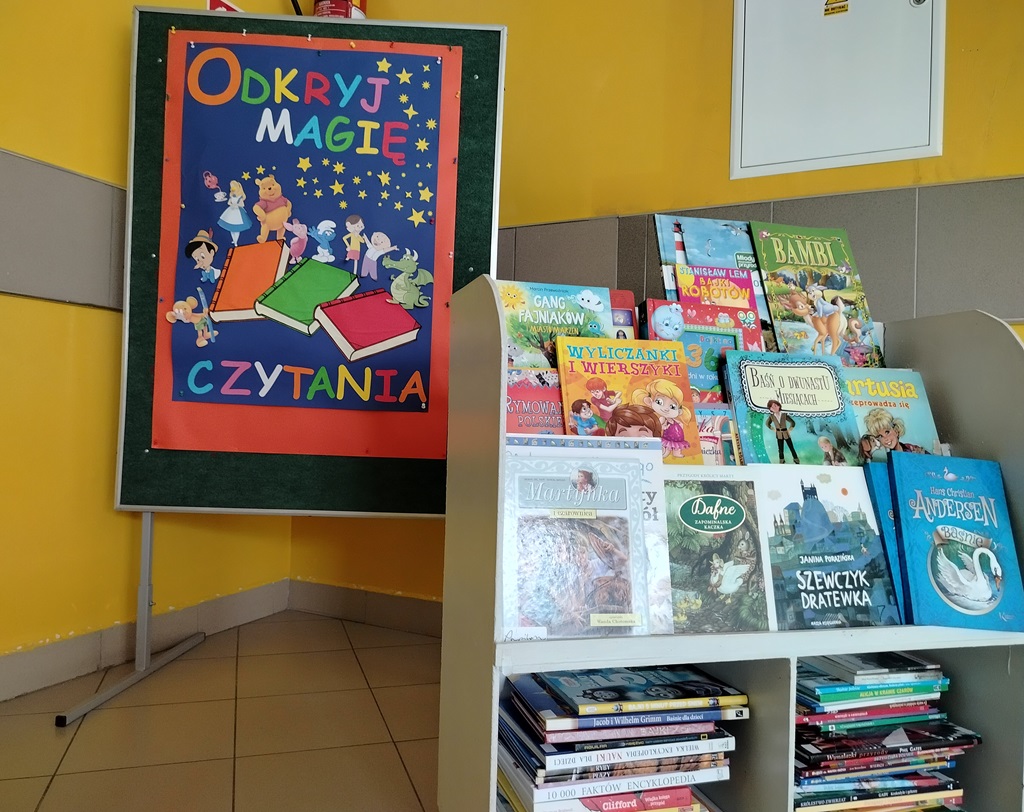 Wystawka podarowanych książek, w tle plakat pt. Odkryj magię czytania