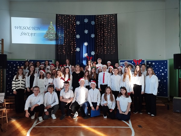 Szkolny chór stoi na tle świątecznej scenografii.