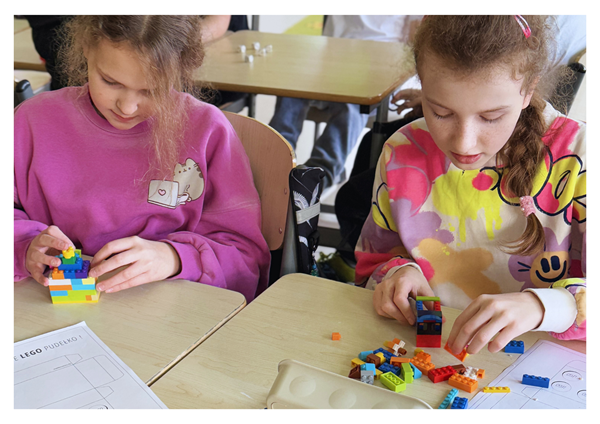 Dwie dziewczynki siedzą przy stoliku i budują z klocków LEGO