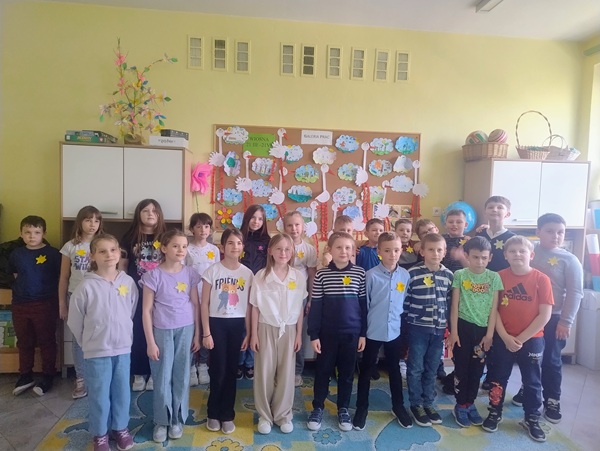 grupka dzieci, która ma przypięte do ubrania żółte żonkile.