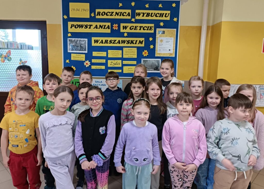 Dzieci stoją pod gazetką wykonaną z okazji rocznicy wybuchu Powstania w Gettcie Warszawskim