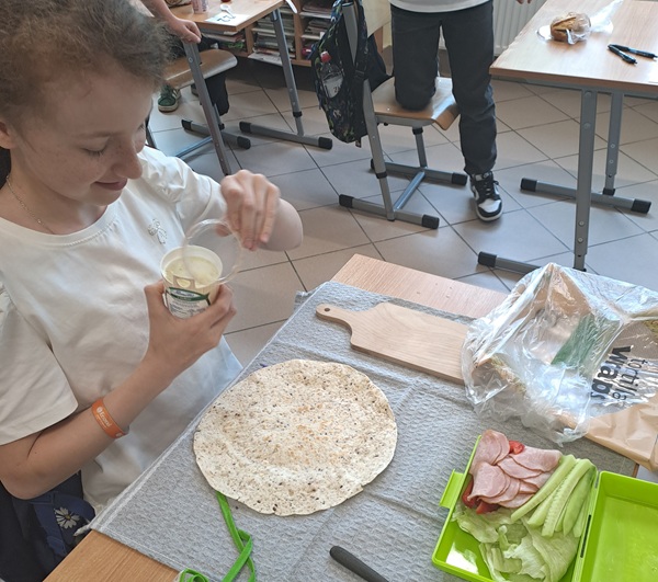 dziewczynka siedząca przy stoliku i przygotowująca zdrową przekąskę.