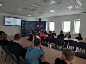 Uczniów siedzą przy stolikach i oglądają prezentację o walorach środowiskowych okolicy.