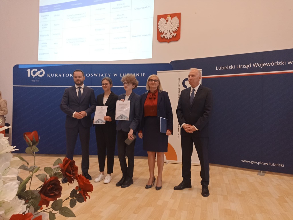 uczniowie naszej szkoły z panią dyrektor stoją z dyplomami, obok przedstawiciele kuratorium
