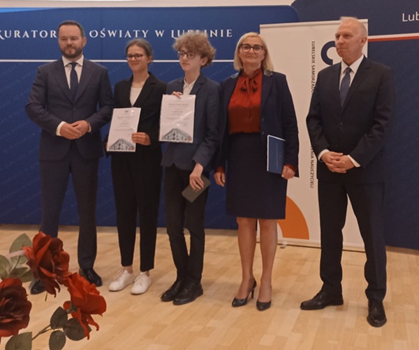 Przedstawiciele kuratorium, dyrektor szkoły i dwoje uczniów szkoły pozują do zdjęcia