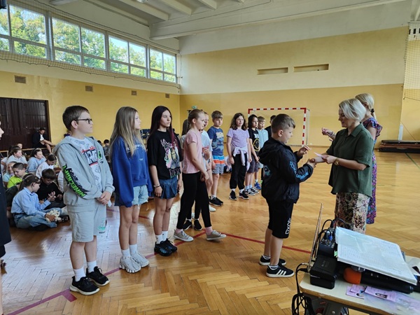 nauczyciel i dyrektor rozdaje uczniom karty rowerowe