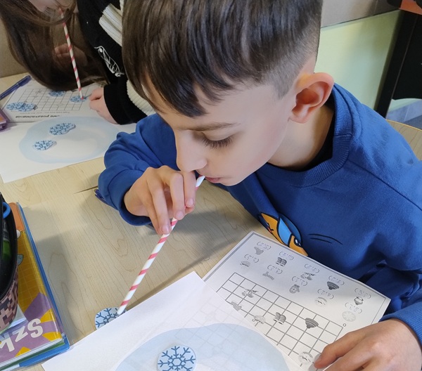 chłopiec, który dmucha rurka kółeczka wykonane z białego papieru