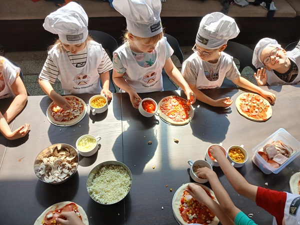 troje dzieci w czapkach kucharskich na pierwszym planie.