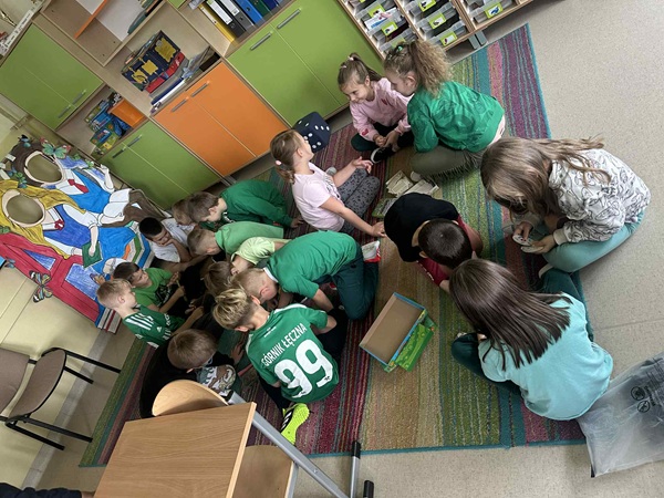 Dzieci siedzą na dywanie, grają w wybrane gry planszowe.