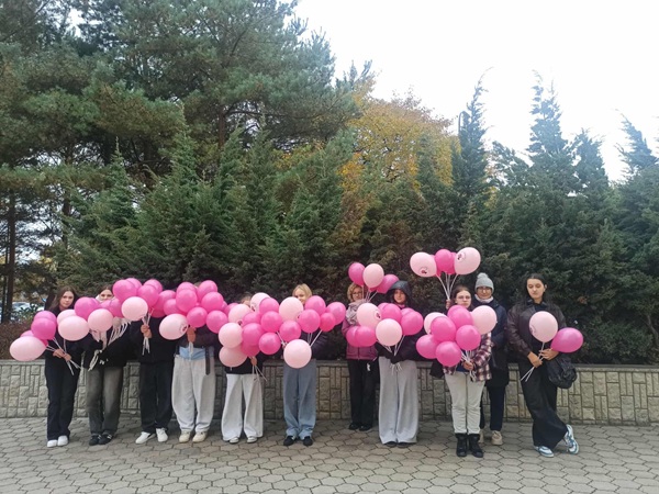 Uczniowie trzymający pęki różowych balonów.