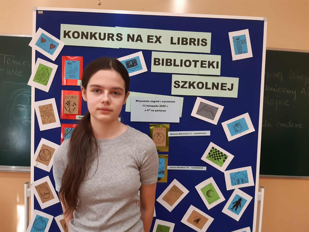 laureatka 1 miejsca prezentuje dyplom na tle tablicy z pracami