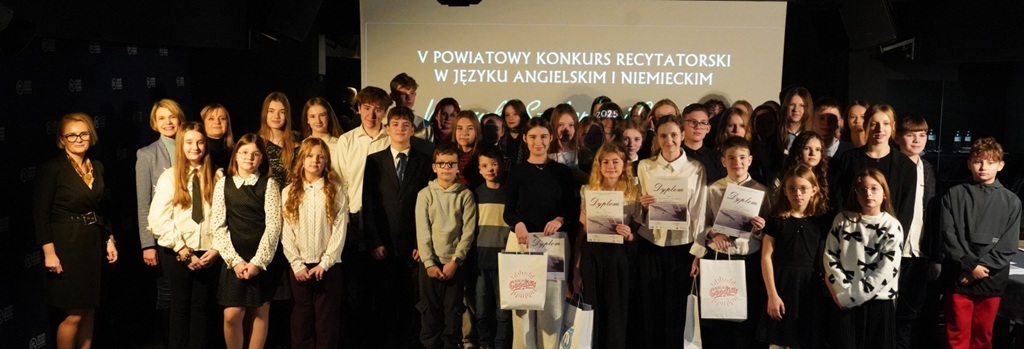 43 uczestników konkursu stoi na tle banneru konkursowego ze swoimi opiekunami