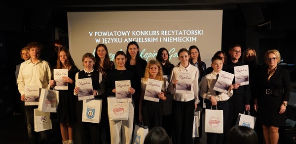 grupa nagrodzonych uczniów stoi trzymając dyplomy i torebki z nagrodami